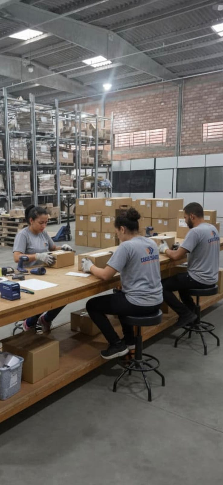 Equipe da Cargo Services trabalhando com conferência e apoio operacional em bancada, com a marca visível nas camisetas.